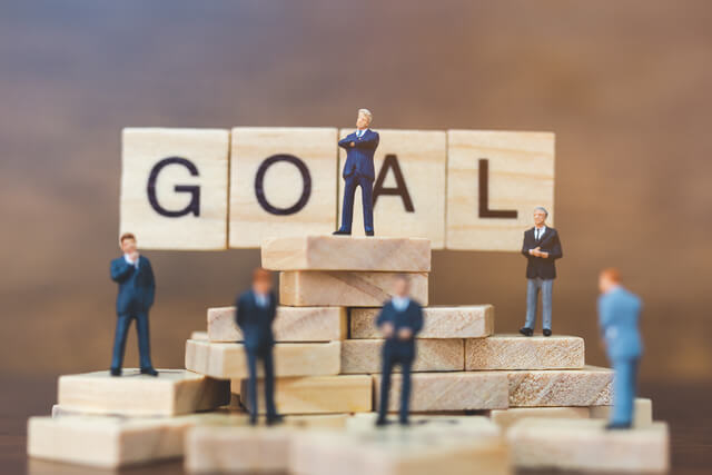 640-miniature-businessmen-standing-on-wooden-blocks-with-the-word-goal-business-career-growth-concept